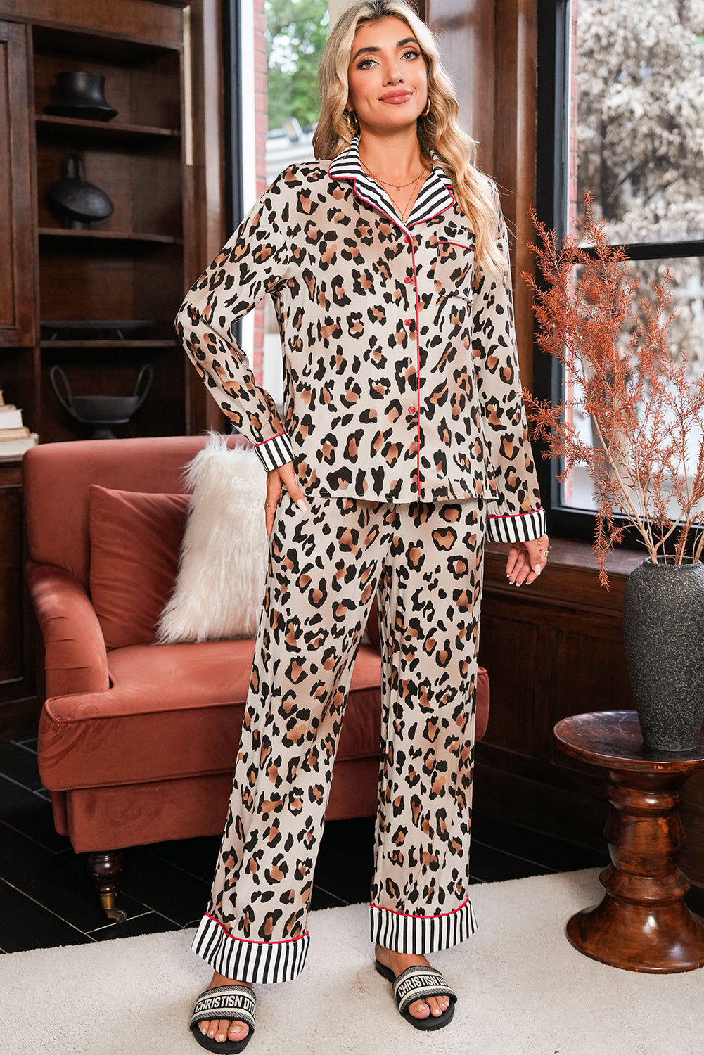 Woman wearing a leopard print pajama set in a cozy living room.