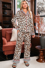 Load image into Gallery viewer, Woman wearing a leopard print pajama set in a cozy living room.
