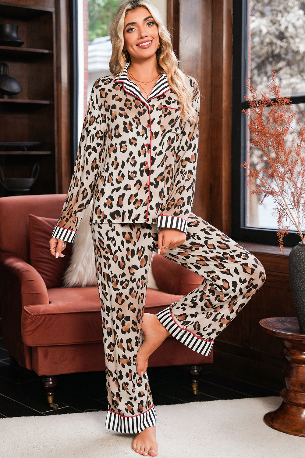 Woman wearing leopard print pajamas with striped cuffs in a cozy living room.
